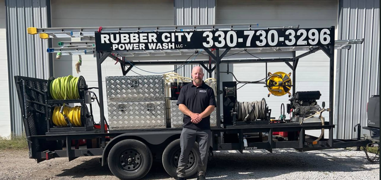 Brian, owner of Rubber City Power Wash, standing in front of the company pressure washing rig