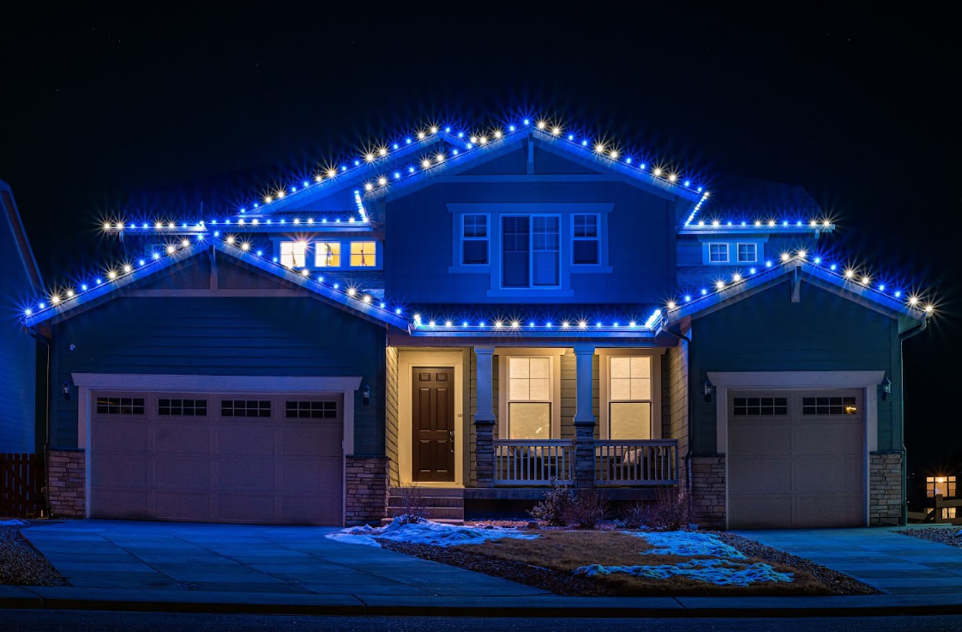 Home with blue and white holiday lighting along the roofline